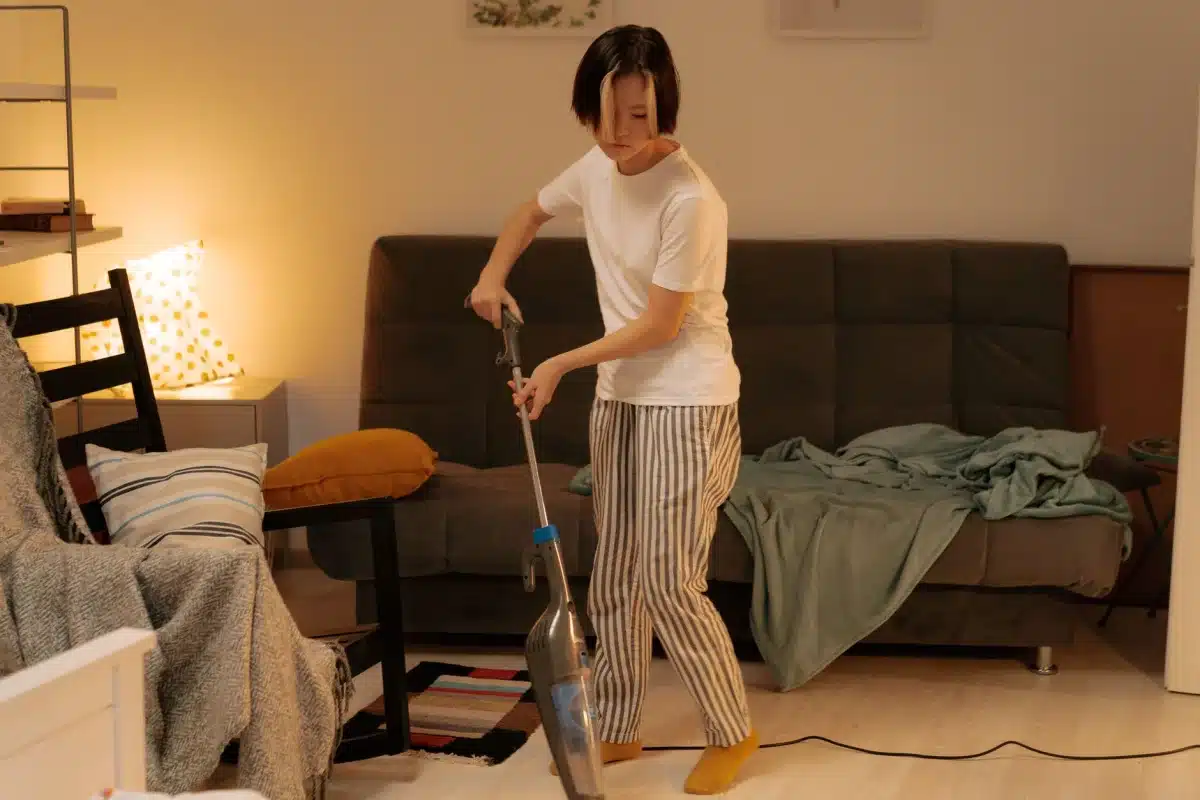 Person vacuuming a living room as part of weekly cleaning tasks